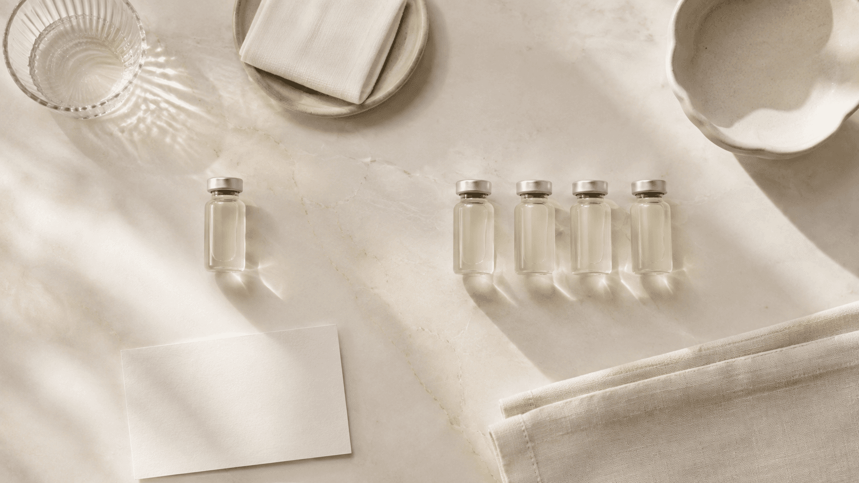 People-free overhead editorial arrangement of six neutral unlabeled wellness vials representing The Wellness Room vitamin shot menu